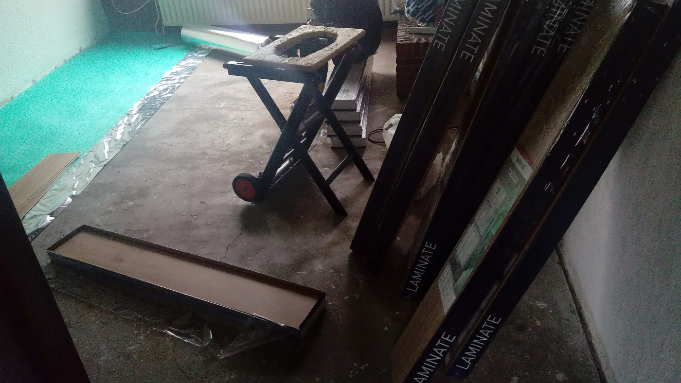 Pakken plaklaminaat op een betonnen ondervloer, klaar om in te schatten hoeveel nodig is